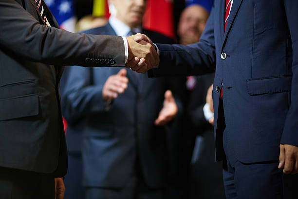 Expressing trust and respect Two politicians handshaking on background of applauding delegates politician stock pictures, royalty-free photos & images