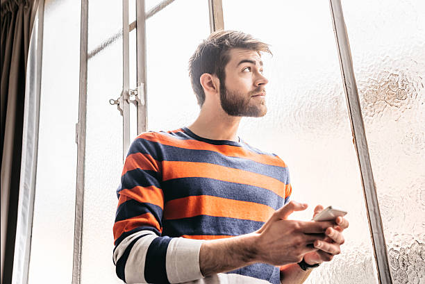 istock handsome pensive bearded young  man with mobile in Paris loft 622979642