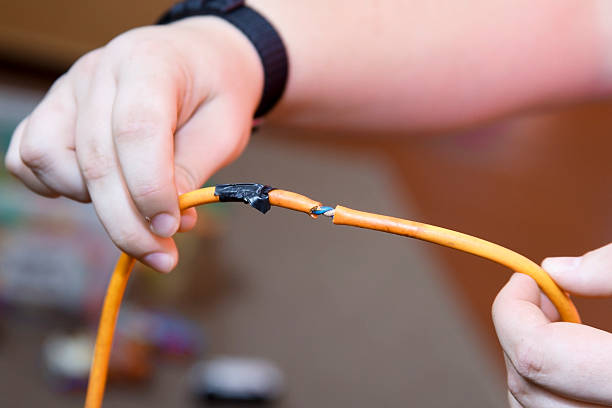 Damaged cable Electrician holding Portable appliance (PAT) test failure due to damaged cable. Badly repaired. power cable stock pictures, royalty-free photos & images