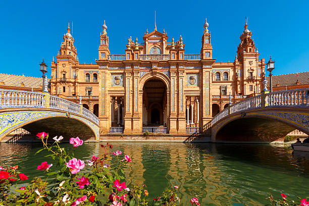 Plaza de Espana at sunny day in Seville, Spain Spain Square or Plaza de Espana in Seville in the sunny summer day, Andalusia, Spain. Flower beds, bridges and channel in the foreground espana stock pictures, royalty-free photos & images