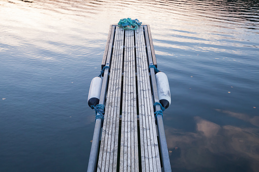 Perspective of small floating pier on still water, European marina, equipment for yachts mooring