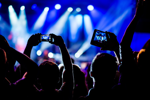 People capturing live music concert through smart phone and digital tablet.