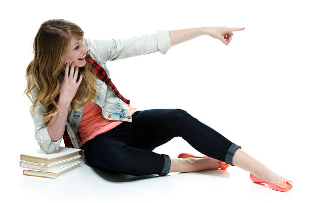istock Cheerful student sitting on floor and pointing 622990862