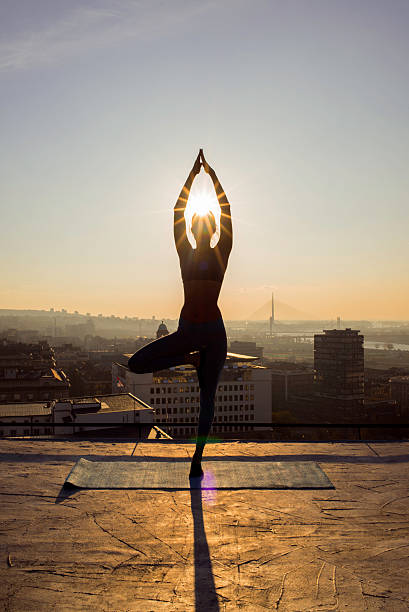 istock woman doing yoga on the rooftop on sunset 622992590