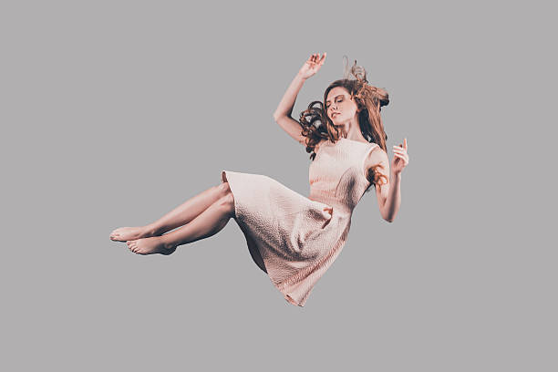 Woman in mid-air. Studio shot of attractive young woman hovering in air levitation stock pictures, royalty-free photos & images