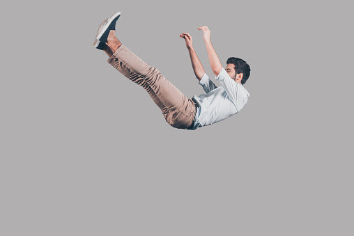 Mid-air shot of handsome young man falling against grey background