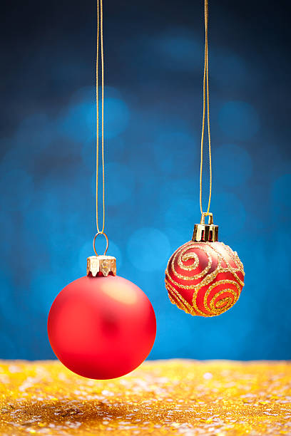 istock Red christmas baubles on gold glitter with blue background 622993736