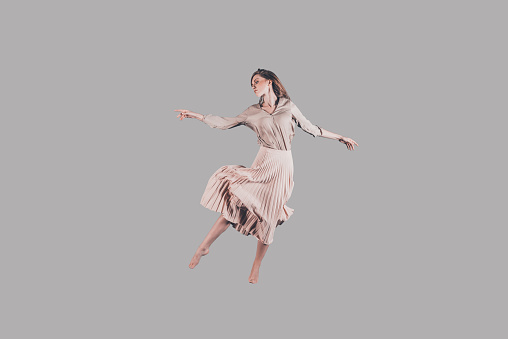 Studio shot of attractive young woman in beautiful dress hovering in air