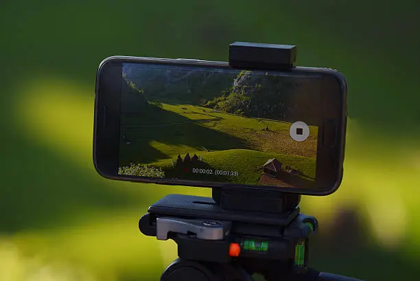 Photo of Smartphone on tripod recording timelapse in sunset mountain landscape