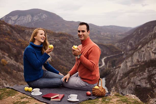 istock Man and wife sitting beside the cliff while eating apple. 623062766