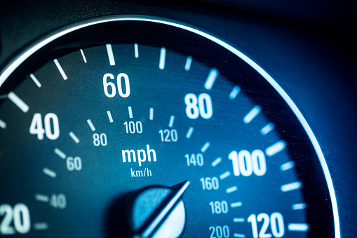 Extreme close up macro image of a car speedometer. The image has a heavy blue tint to it. Horizontal colour image with copy space.