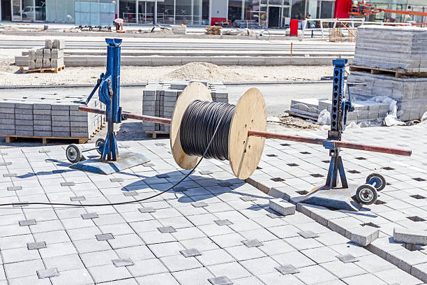 Cable spool is on the axle until worker unwinds wire.