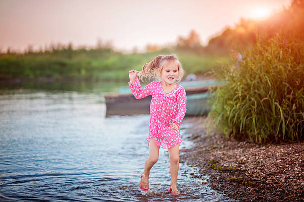 istock Little girl jumping over the water 623065968