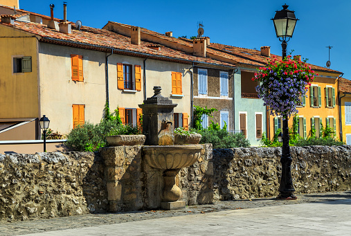 Spectacular colorful traditional Provence houses,decorated street with beautiful flowers and graven water fountain,Moustiers-Sainte-Marie,Provence,France,Europe