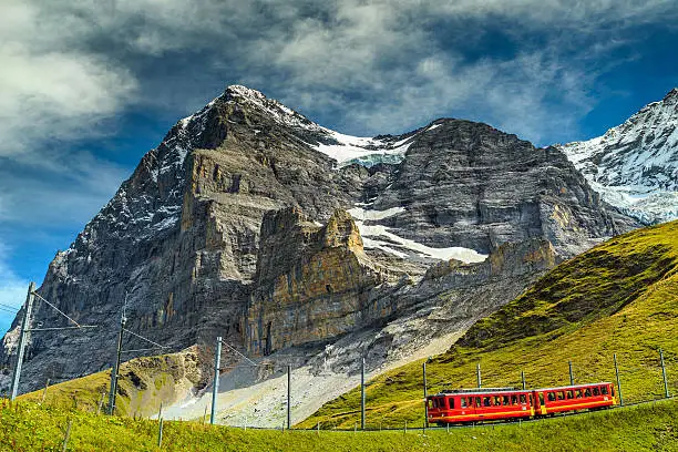 Spectacular famous electric red tourist train coming down from the Jungfraujoch station(top of Europe) in Kleine Scheidegg,Bernese Oberland,Switzerland,Europe