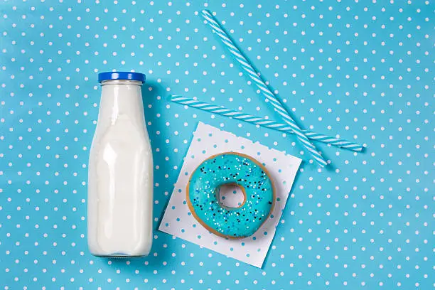 Photo of Blue donut, milk and straws on polka dots blue background