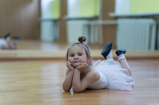 Little girl in gymnastic leotard in a room with mirrors