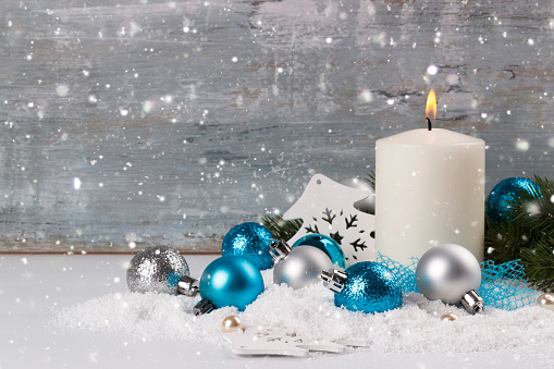 Christmas decoration with candle on snow, blue wooden background