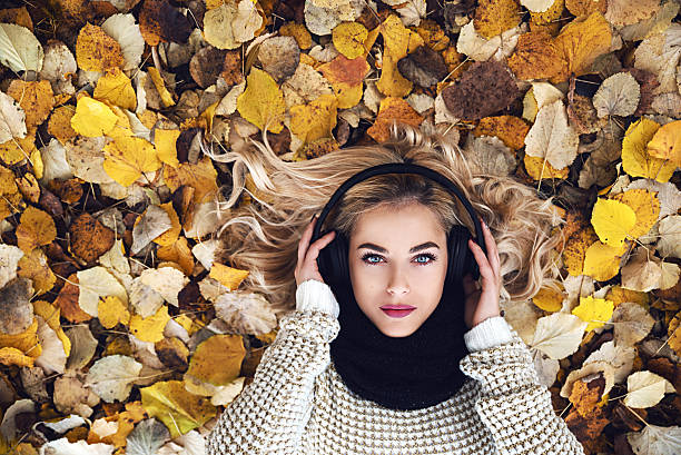 Beautiful girl with headphones Girl with headphones laying in park and listening music blond hair fine art portrait portrait women stock pictures, royalty-free photos & images