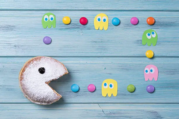 Powdered donut with smiley face and colored smarties and ghosts frame, blue wooden background