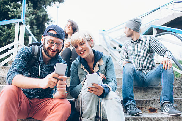 istock Four young people sitting on stairs and using smart phones 623095234
