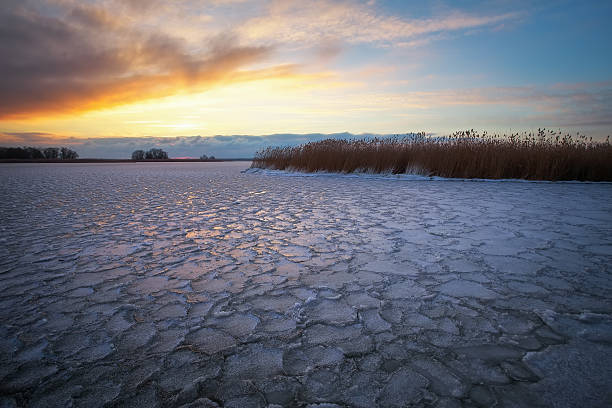istock Winter landscape with frozen lake and sunset sky. Composition of 623098376