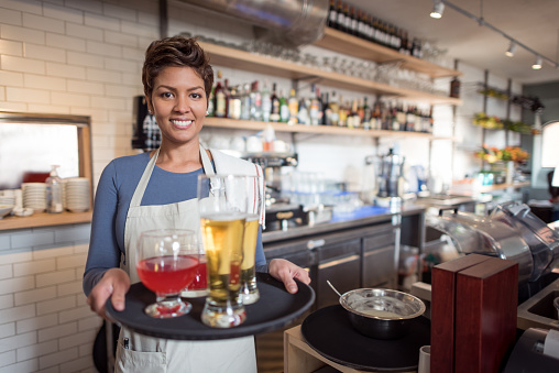 Waitress working at a restaurant carrying a tray and looking happy