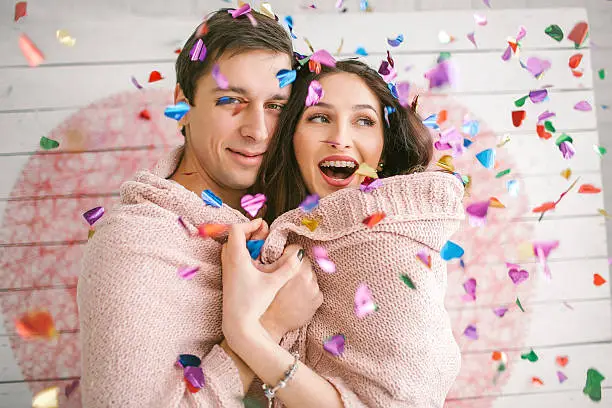 Young couple in love embracing under confetti in decorated studio