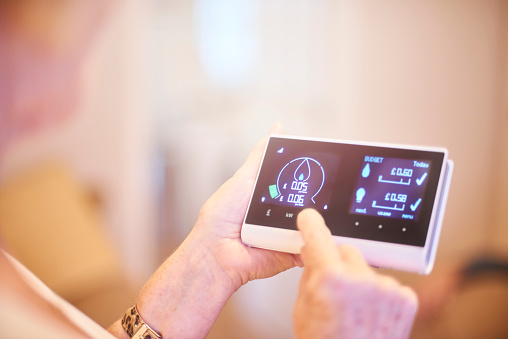 Close up of home owner checking energy consumption on smart meter home technology. They can see their energy consumption and billing all in one place and live costs. Graphics and all identifying have been altered.