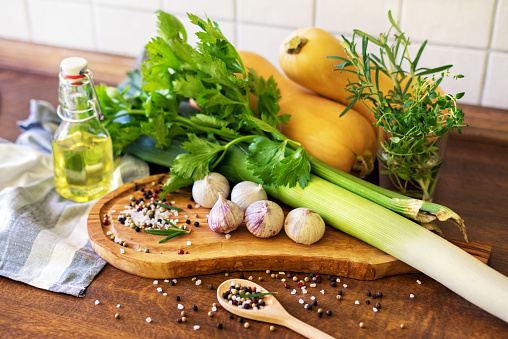 Organic green vegatables and cutting board on a white background. Cucumbers, garlic, green pea, parsley, basil, zucchini.