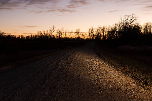 Empty single lane country road at sunset.