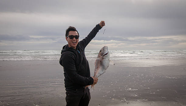 o homem pegou peixe. - murawai beach - fotografias e filmes do acervo