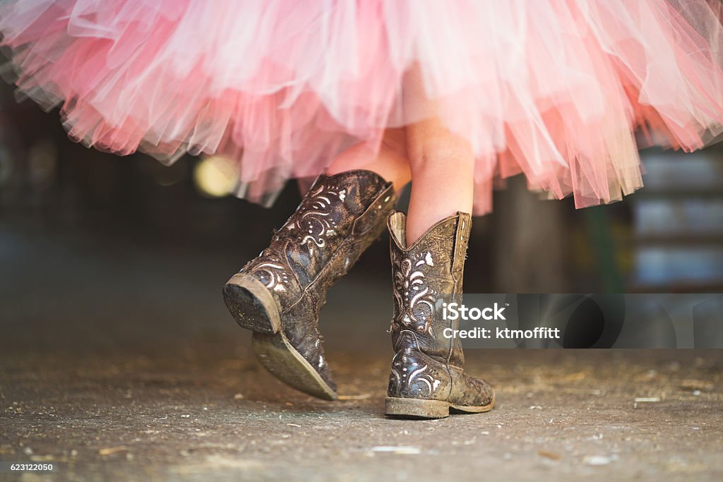 Tutu and Cowgirl Boots Princess Cowgirl. Little cowgirl walking though a barn in her boots and pink tutu in the afternoon sun. Cowboy Boot Stock Photo