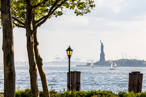 The Battery Park esplanade in Lower Manhattan. The Statue of Liberty and Liberty Island is seen in the background
