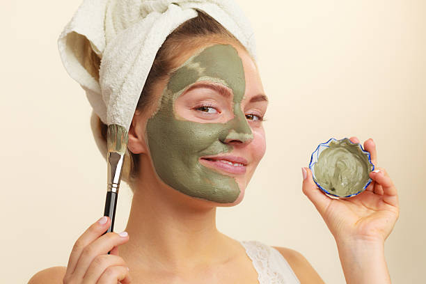 istock Woman applying with brush clay mud mask to her face 623125200
