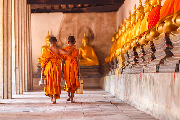 due novizi che camminano tornano e parlano nel vecchio tempio - novice buddhist monk foto e immagini stock