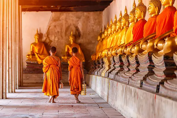 Two novices walking return and talking in old temple at sunset time, Ayutthaya Province, Thailand