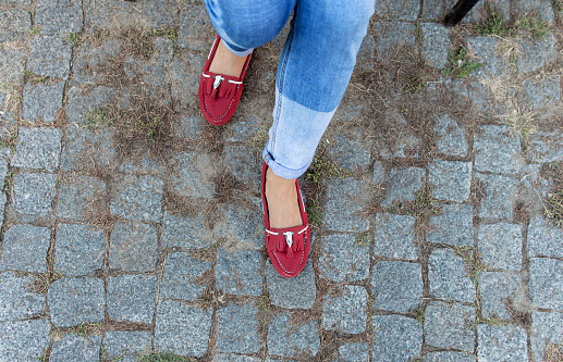 Womens foot close up in jeans and red loafers. Copy space