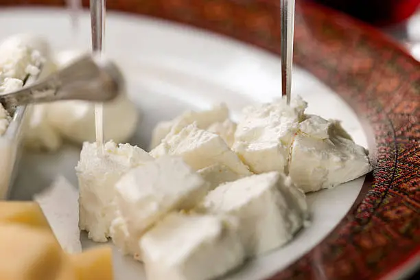 Feta cheese slices with skewers close up on plate