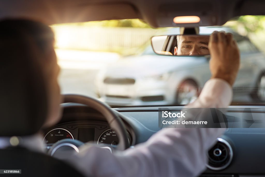 Man adjusting a rearview mirror Man sitting in a car and adjusting rearview mirror, car interior Car Stock Photo