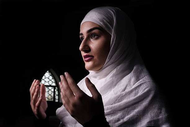 istock Girl With Hijab Isolated in dark praying 623187254