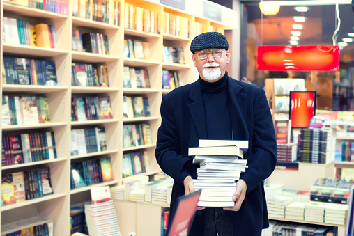 Man with pile of book in bookstore