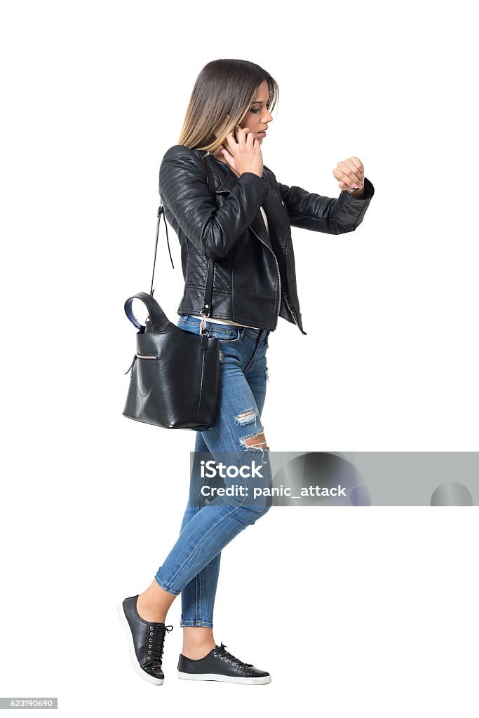 Busy casual girl on the phone checking time Side view of busy casual fashion girl on the phone checking time on her watch. Full body length portrait isolated over white background Women Stock Photo