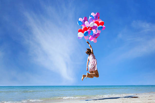 concepto de sueño, chica volando con globos multicolores, salto - jumping freedom women beach fotografías e imágenes de stock