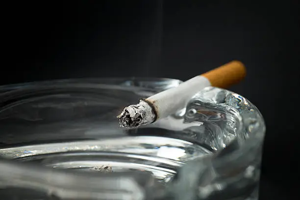Burning cigarette with ashtray , black background
