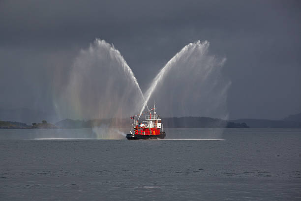 пожарная лодка делает радужный салют - fire boat стоковые фото и изображения