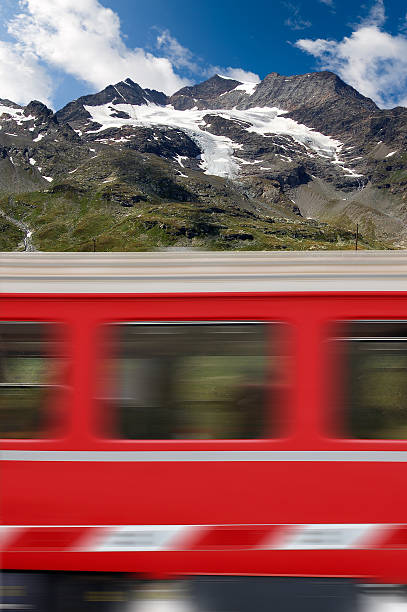 Red train in motion and the Bernina Alps with the glacier in the background, Engadine, Switzerland, Europe