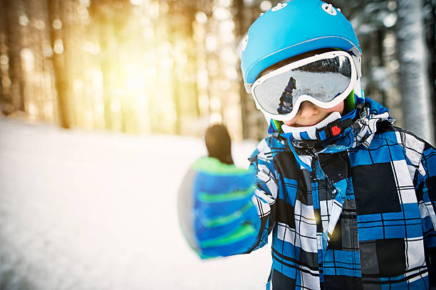 garotinho esquiando na floresta nevada no dia ensolarado de inverno - skiing snow skiing helmet fun - fotografias e filmes do acervo