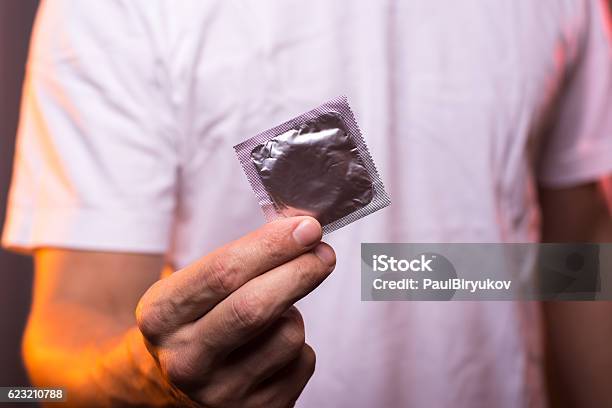 Unknown Man In White Shirt Holding Condom In Hand Stock Photo - Download Image Now - Condom, Holding, Men