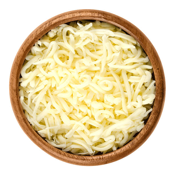 Shredded mozzarella pizza cheese in wooden bowl over white Shredded mozzarella pizza cheese in wooden bowl over white. Cheddar like semi hard Italian cheese made from milk, covered with corn starch. Isolated macro food photo close up from above. mozzarella stock pictures, royalty-free photos & images